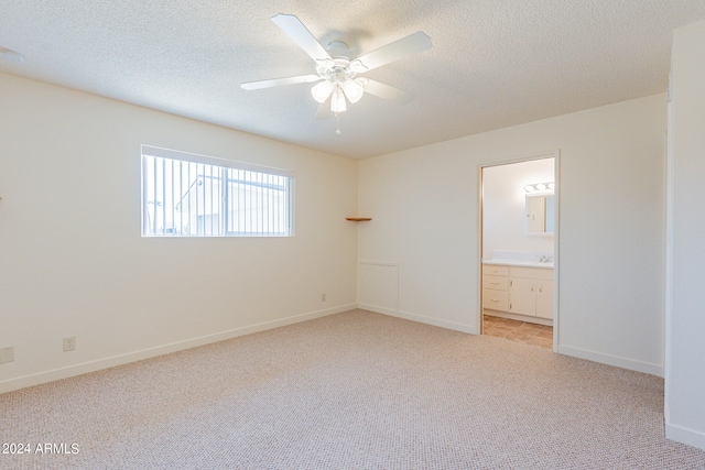 unfurnished bedroom featuring connected bathroom, a textured ceiling, light colored carpet, and ceiling fan