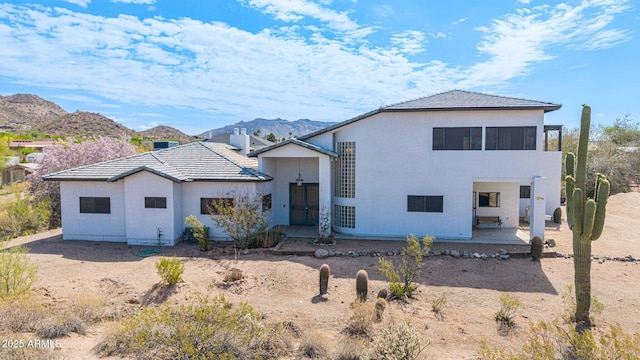 view of front of home featuring a patio area, a tile roof, stucco siding, and a mountain view