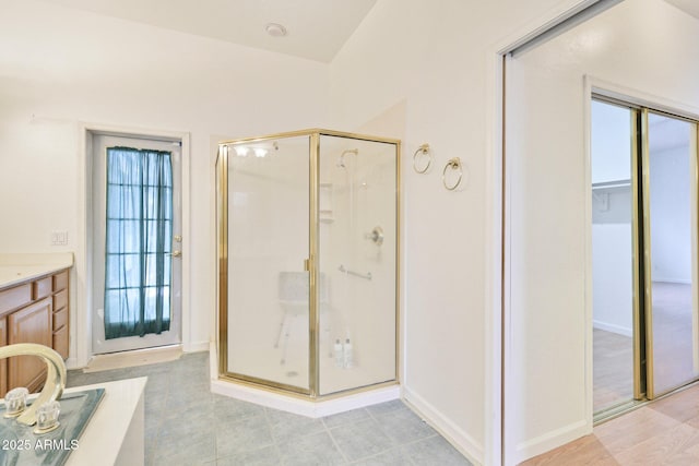 full bath featuring a shower stall, vanity, and baseboards