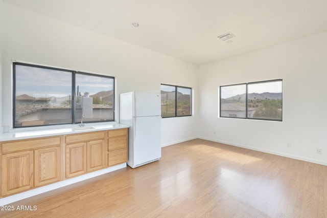 empty room with a sink, light wood-type flooring, and baseboards