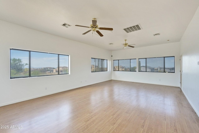 empty room featuring a ceiling fan, light wood finished floors, and baseboards