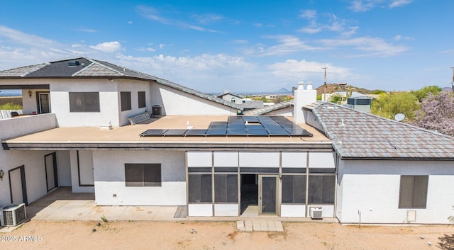 back of house with solar panels, stucco siding, and a sunroom