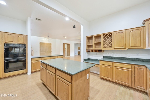 kitchen featuring light wood finished floors, a kitchen island, open shelves, dark countertops, and recessed lighting