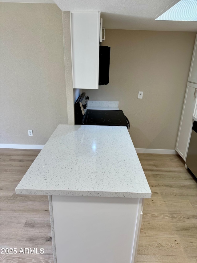 6810 N 35th Ave Unit H, Phoenix, AZ 85017 - kitchen featuring range with electric stovetop, white cabinetry, baseboards, light wood-style flooring, and light stone countertops