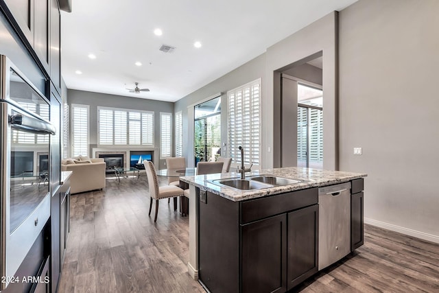 kitchen with ceiling fan, sink, stainless steel dishwasher, a kitchen island with sink, and dark hardwood / wood-style flooring