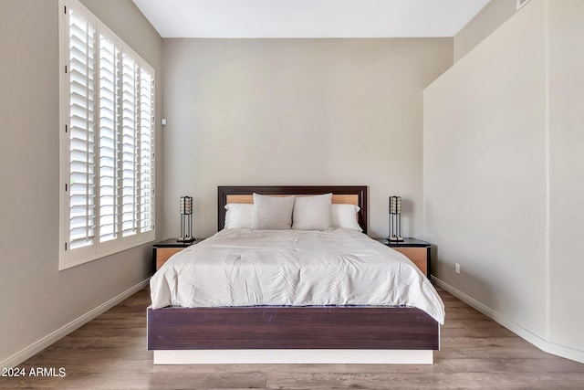 bedroom with hardwood / wood-style flooring and multiple windows