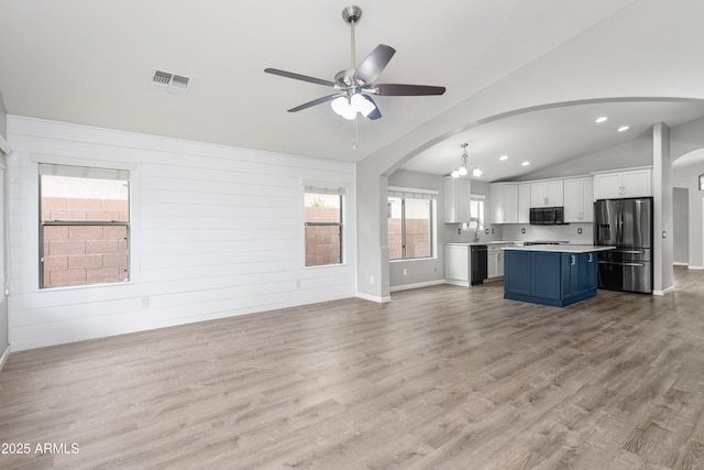 1015 E Penny Ln, San Tan Valley, AZ 85140 - unfurnished living room with a ceiling fan, arched walkways, vaulted ceiling, a chandelier, and light wood-type flooring
