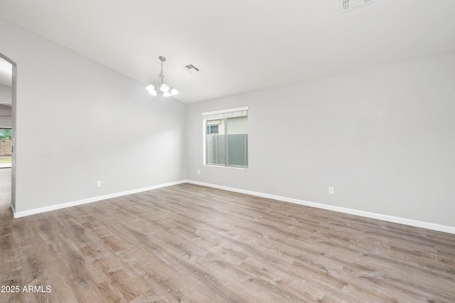 1015 E Penny Ln, San Tan Valley, AZ 85140 - unfurnished room featuring healthy amount of natural light, a chandelier, wood finished floors, arched walkways, and lofted ceiling