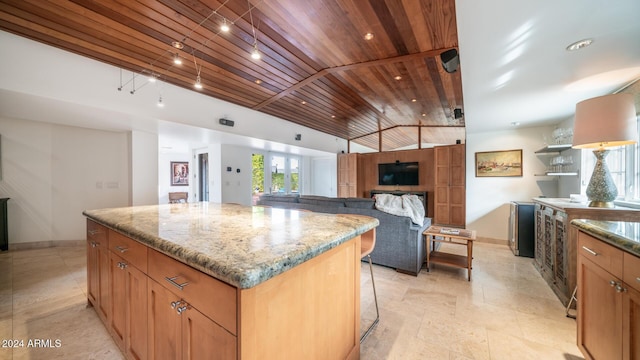 kitchen featuring a center island, light stone counters, vaulted ceiling, and wood ceiling