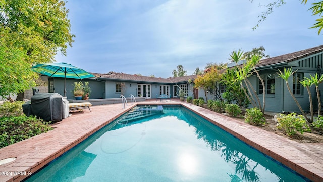 view of swimming pool featuring french doors, a patio, and grilling area