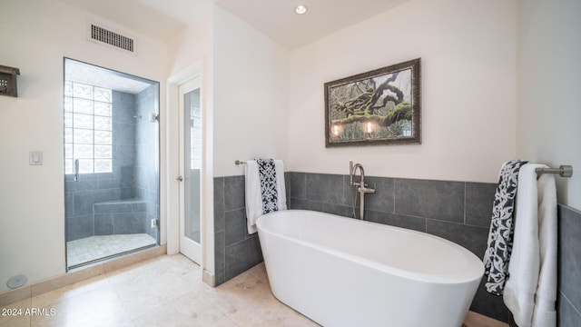 bathroom featuring tile patterned flooring, separate shower and tub, and tile walls