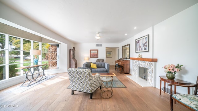 living room featuring ceiling fan, light hardwood / wood-style floors, and a fireplace