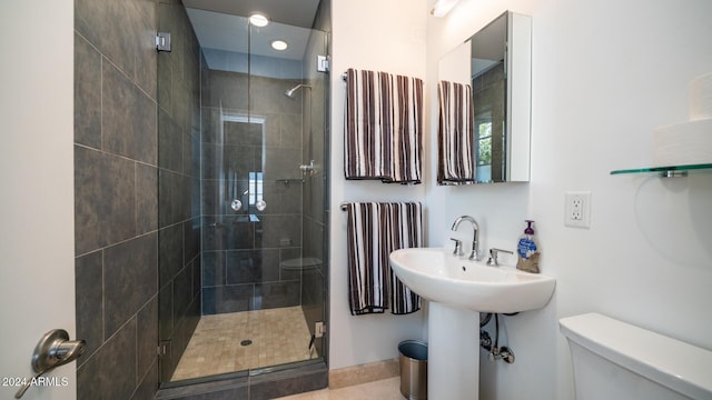 bathroom with tile patterned floors, toilet, a shower with shower door, and sink