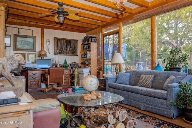 living room featuring beam ceiling, ceiling fan, hardwood / wood-style floors, and wooden walls