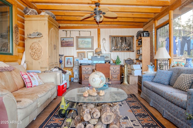 living room with wooden walls, ceiling fan, light wood-type flooring, and beamed ceiling