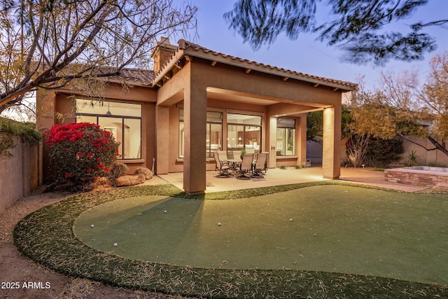 back house at dusk featuring a patio area