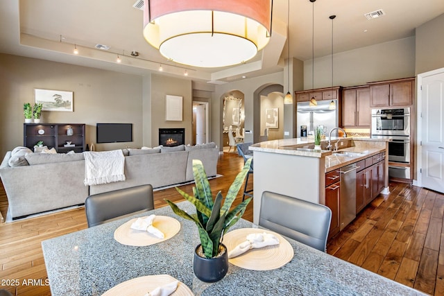 dining room featuring sink, a towering ceiling, a tray ceiling, and dark hardwood / wood-style floors