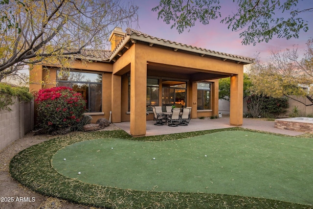 back house at dusk with a patio area