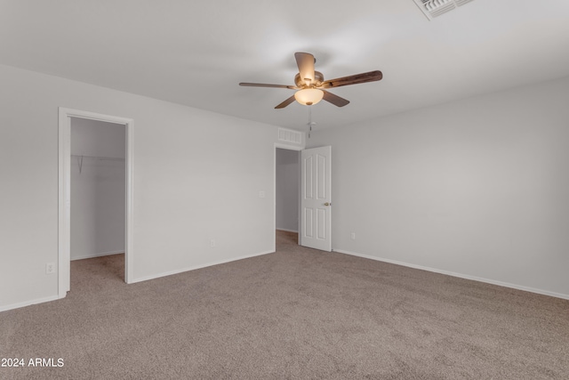 unfurnished bedroom featuring ceiling fan, a closet, carpet floors, and a walk in closet