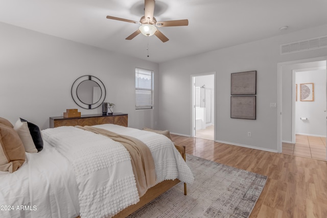 bedroom with light hardwood / wood-style flooring, ensuite bath, and ceiling fan