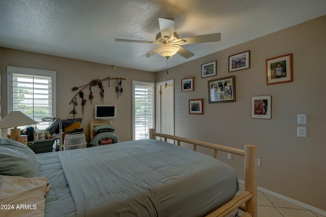 bedroom featuring ceiling fan, a textured ceiling, and light tile patterned floors