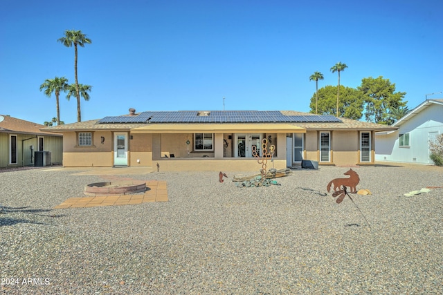 back of house featuring a patio, solar panels, an outdoor fire pit, and cooling unit