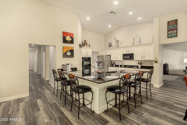 13609 W Vermont Ave, Litchfield Park, AZ 85340 - kitchen with high vaulted ceiling, a kitchen bar, a sink, a spacious island, and black appliances