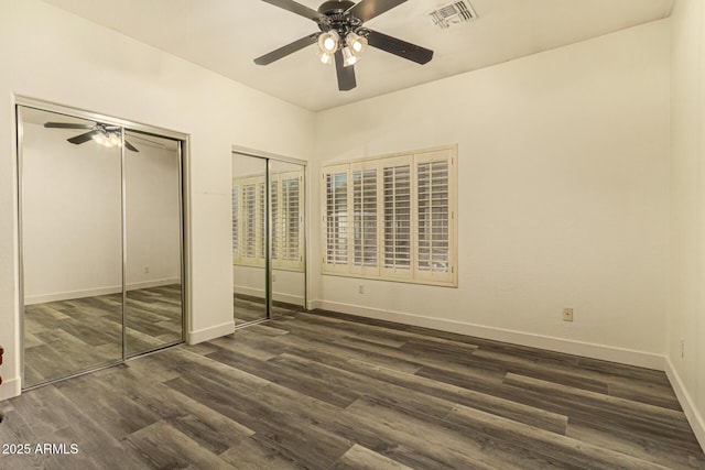 13609 W Vermont Ave, Litchfield Park, AZ 85340 - unfurnished bedroom featuring two closets, baseboards, dark wood finished floors, visible vents, and a ceiling fan