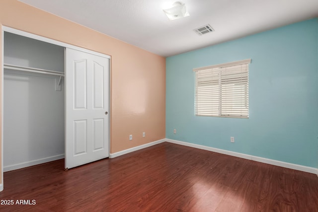 unfurnished bedroom with dark hardwood / wood-style flooring and a closet