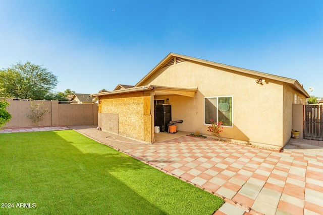 back of house with a lawn and a patio