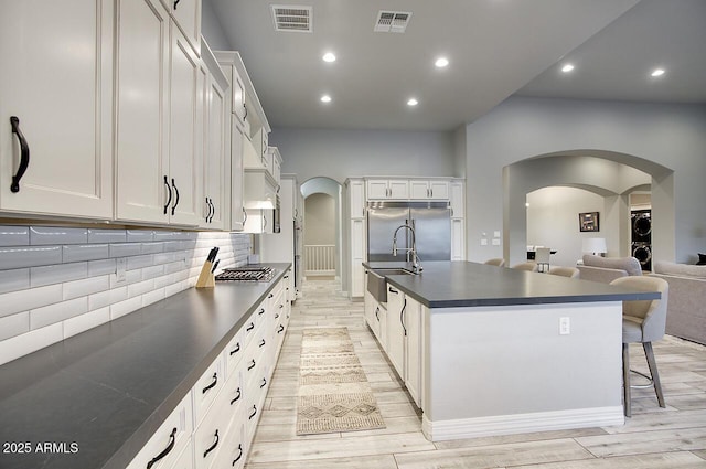 kitchen featuring arched walkways, dark countertops, white cabinetry, and visible vents