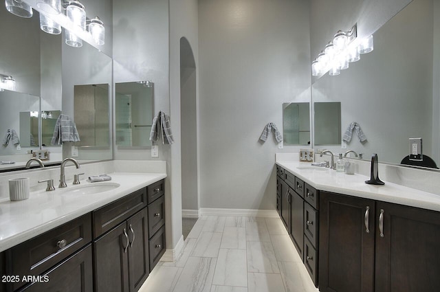 bathroom featuring baseboards, two vanities, and a sink