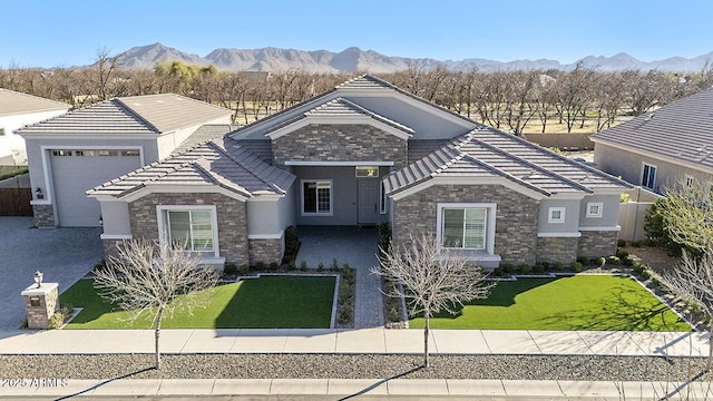 view of front of home featuring stone siding, a front lawn, a tiled roof, and a mountain view