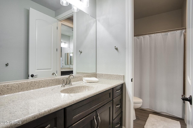 bathroom with toilet, a shower with shower curtain, wood finished floors, and vanity