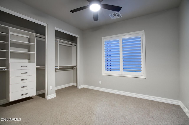 unfurnished bedroom with carpet floors, baseboards, visible vents, and multiple closets