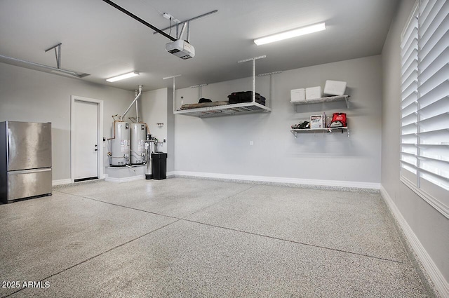 garage with a garage door opener, freestanding refrigerator, gas water heater, and baseboards