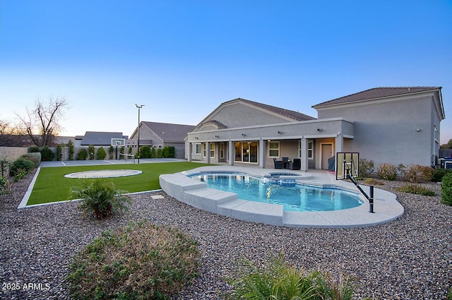 view of pool with a pool with connected hot tub, a lawn, and a patio