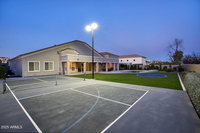 view of tennis court featuring community basketball court, fence, and a yard