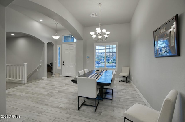 dining room with arched walkways, a notable chandelier, visible vents, baseboards, and light wood finished floors