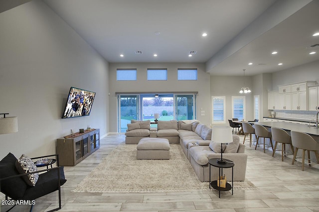 living room featuring recessed lighting, visible vents, a towering ceiling, and light wood finished floors