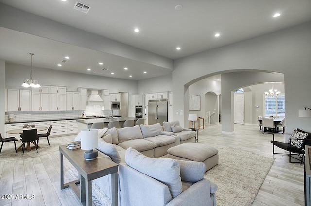 living area featuring a chandelier, light wood-type flooring, visible vents, and recessed lighting