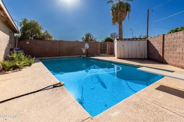 view of swimming pool with a diving board and a storage unit