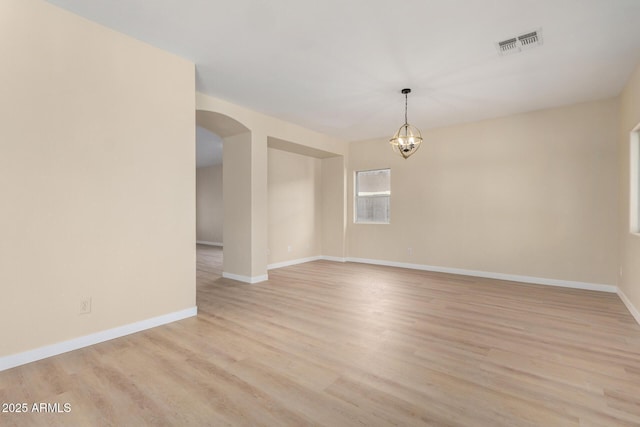 12426 W Adams St, Avondale, AZ 85323 - spare room featuring arched walkways, light wood finished floors, baseboards, and a chandelier