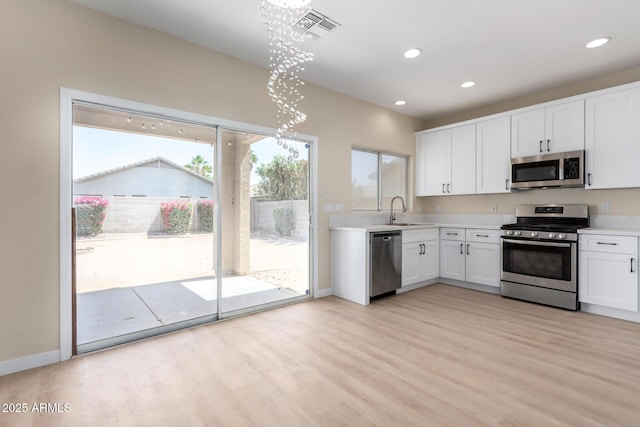 12426 W Adams St, Avondale, AZ 85323 - kitchen featuring stainless steel appliances, light wood-type flooring, light countertops, white cabinets, and recessed lighting