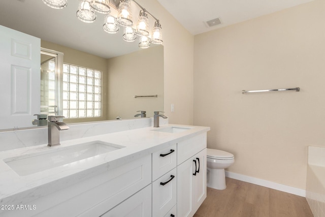 12426 W Adams St, Avondale, AZ 85323 - bathroom with toilet, wood finished floors, double vanity, baseboards, and a chandelier