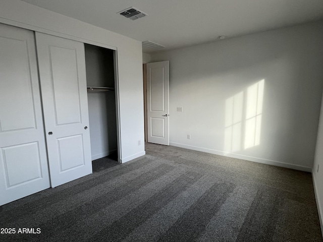 unfurnished bedroom featuring dark carpet and a closet