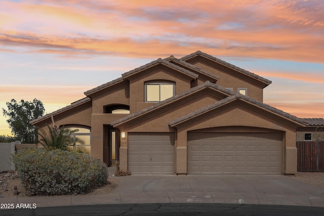 view of front facade with a tile roof, concrete driveway, and stucco siding