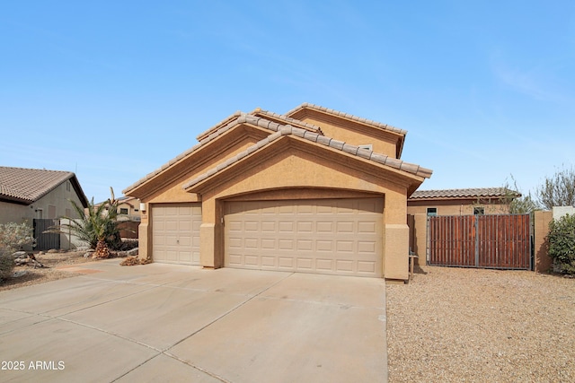 mediterranean / spanish-style house featuring concrete driveway, a tiled roof, a gate, fence, and stucco siding