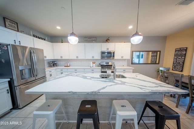 2361 N 212th Dr, Buckeye, AZ 85396 - kitchen with appliances with stainless steel finishes, backsplash, a kitchen bar, white cabinets, and recessed lighting