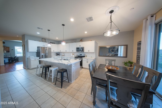 2361 N 212th Dr, Buckeye, AZ 85396 - kitchen featuring stainless steel appliances, tasteful backsplash, light tile patterned floors, a kitchen bar, and recessed lighting